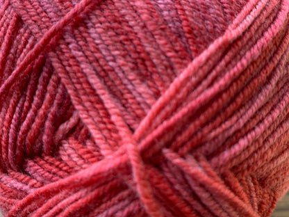 Warm mid-pink coloured hues "Rose Hip" ball of superfine 4 ply Merino on white background